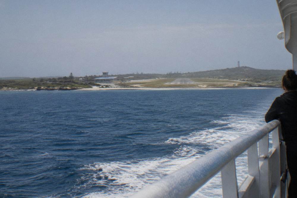 Ferry cutting across open water with Rottnest Island's coastline appearing on the horizon